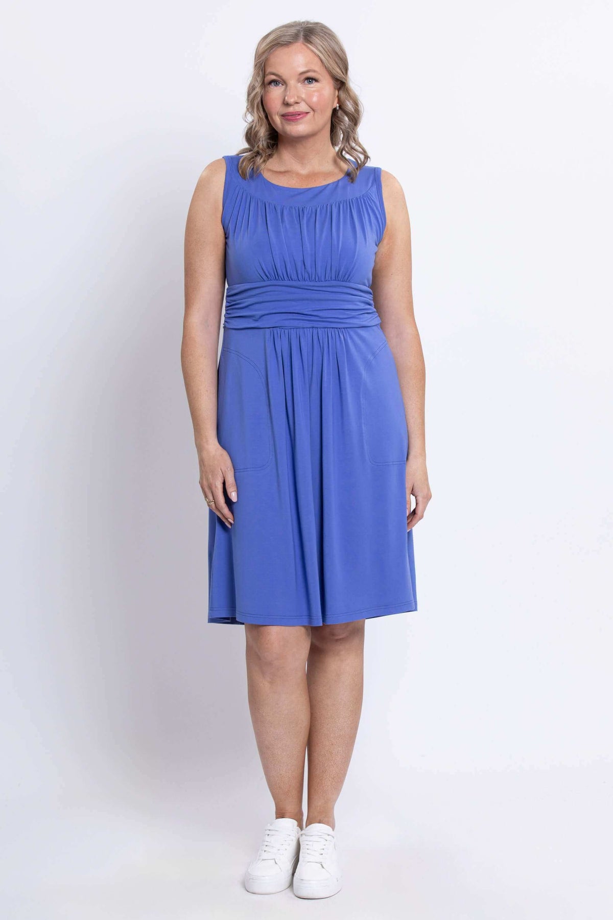 Front view of woman wearing a sleeveless violet ruched dress with waistband and pockets