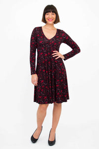 Front view of woman with hand on hip, wearing black and red floral fit and flare dress