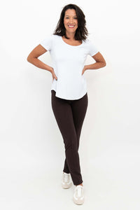 Woman smiling wearing Nadia slim-line brown pants and a white top, front view