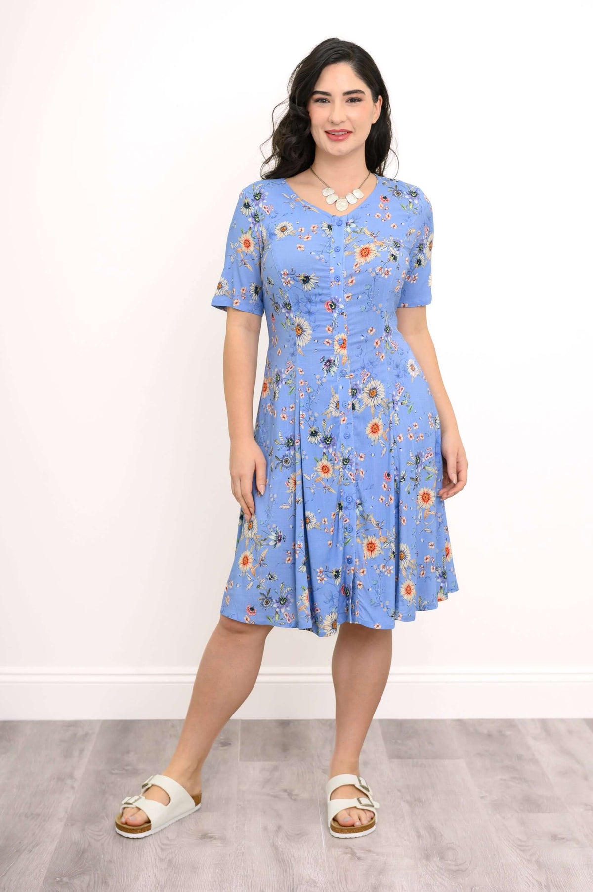 Front view of a woman in a blue floral dress with short sleeves and A-line skirt