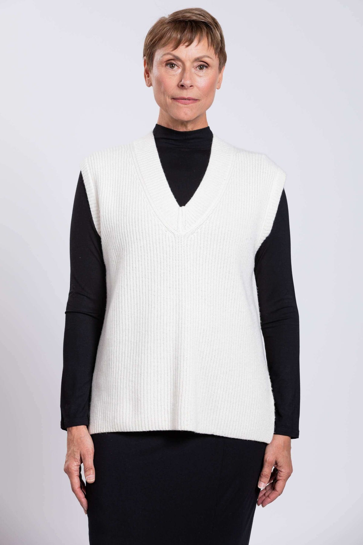Front view of woman wearing boxy white wool-cashmere sweater vest over black top