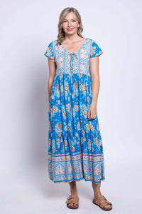 Woman in a blue floral midi dress with tan sandals, standing front view