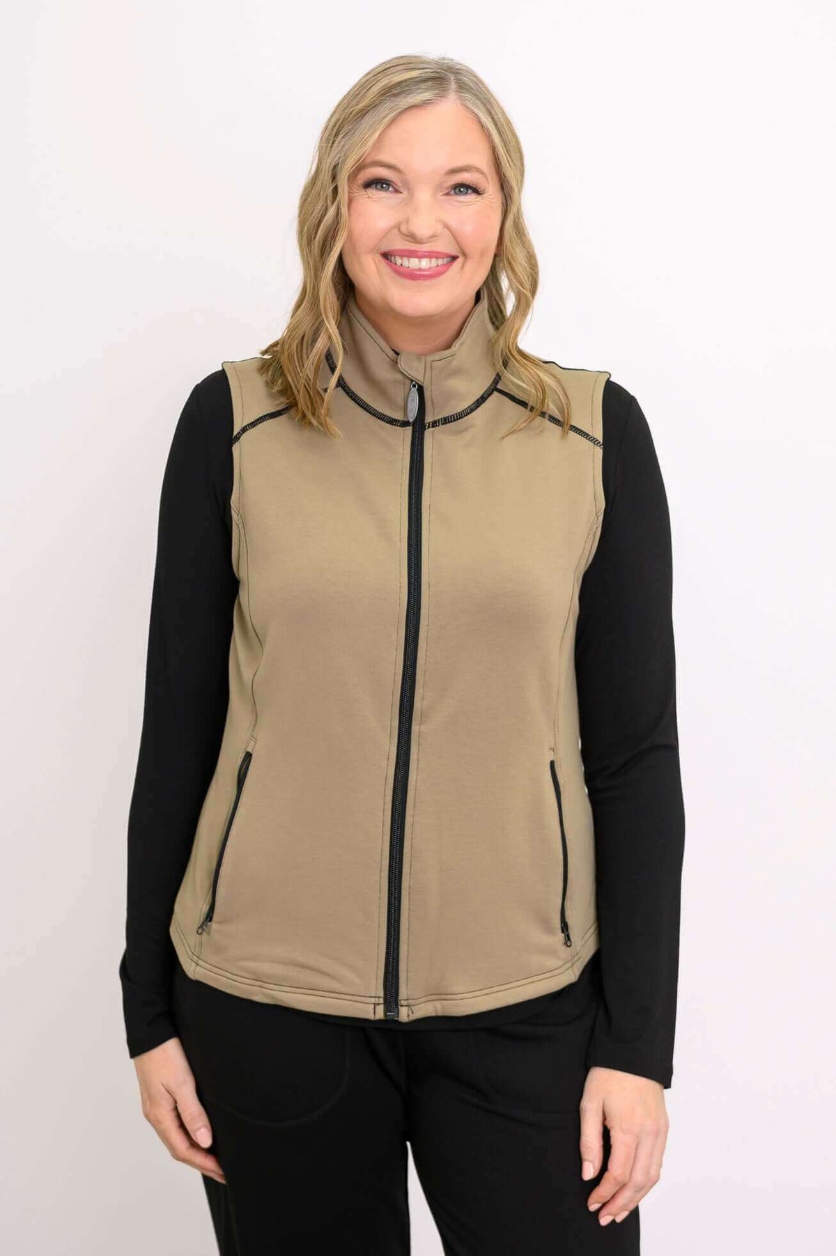 Front view of woman wearing tan Hartford Utility Vest over black sleeves