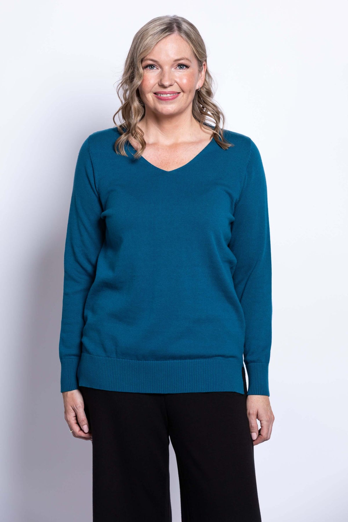 Front view of woman wearing teal V-neck cotton sweater with ribbed cuffs and hem