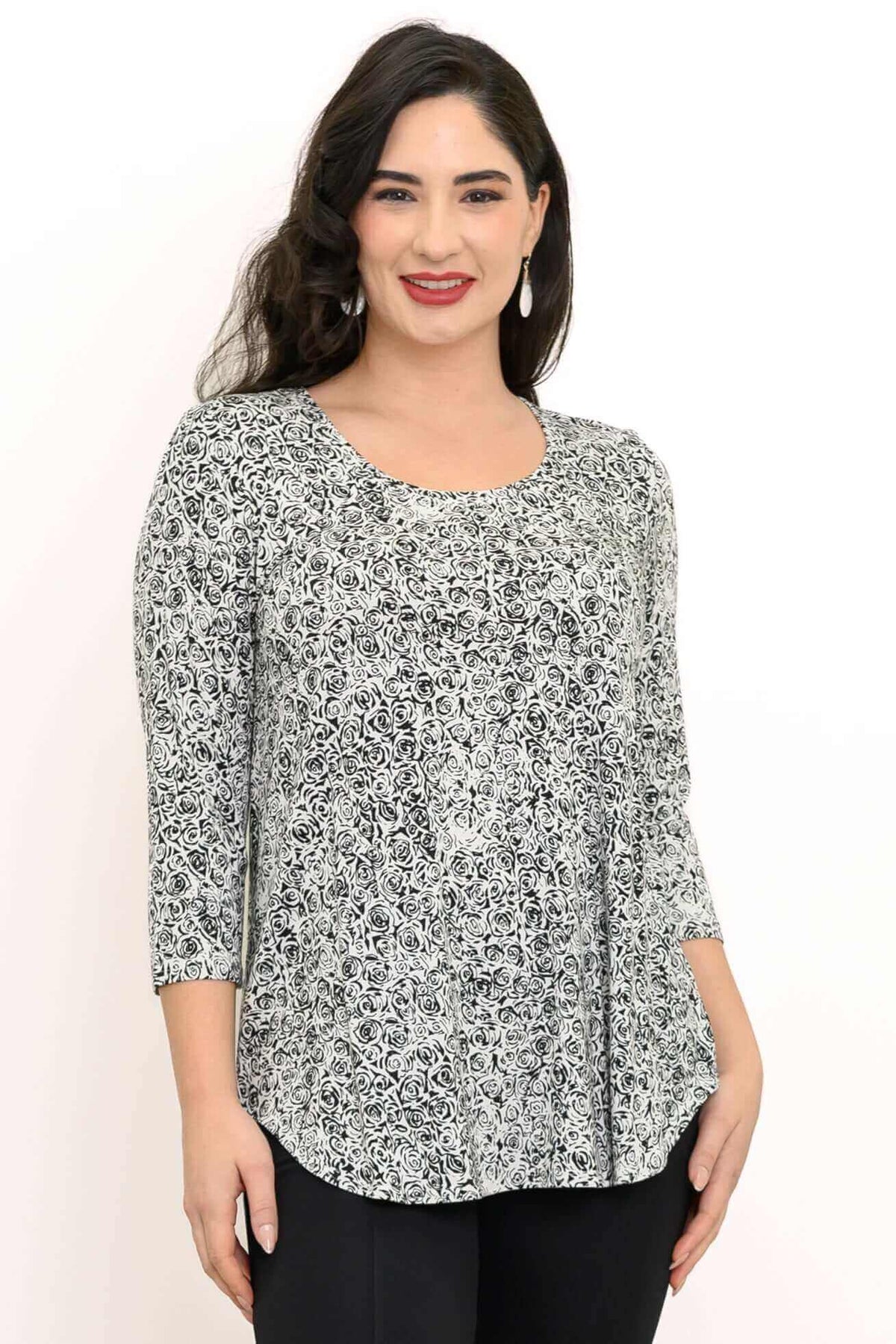 Close up front view of woman wearing 3/4 sleeve top with black and white small rose print