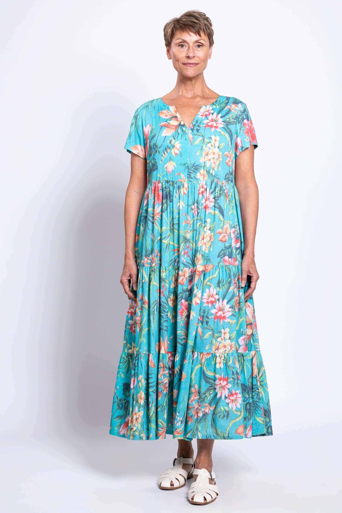 Front view of woman wearing a turquoise floral maxi dress with tiered skirt