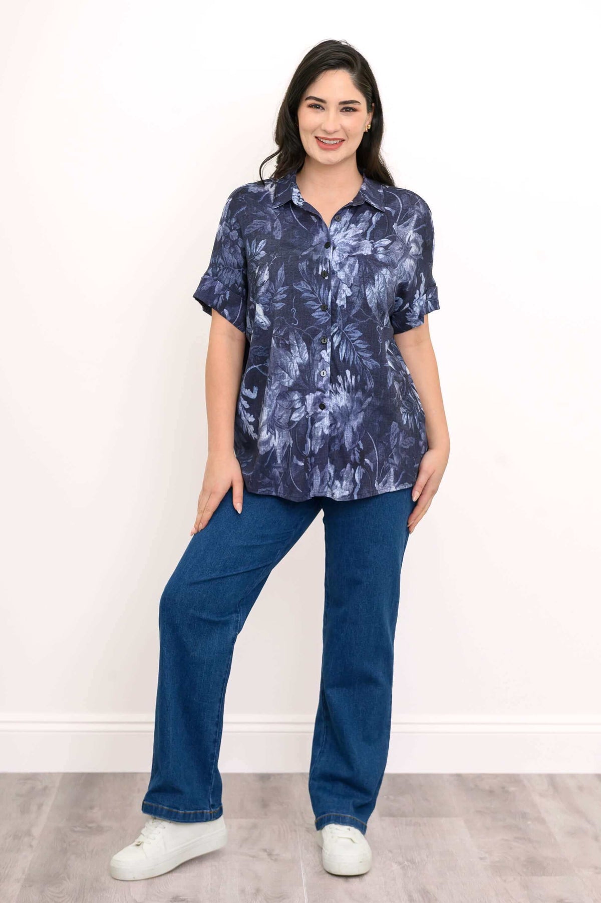 Front view of woman wearing navy floral blouse with jeans, relaxed pose