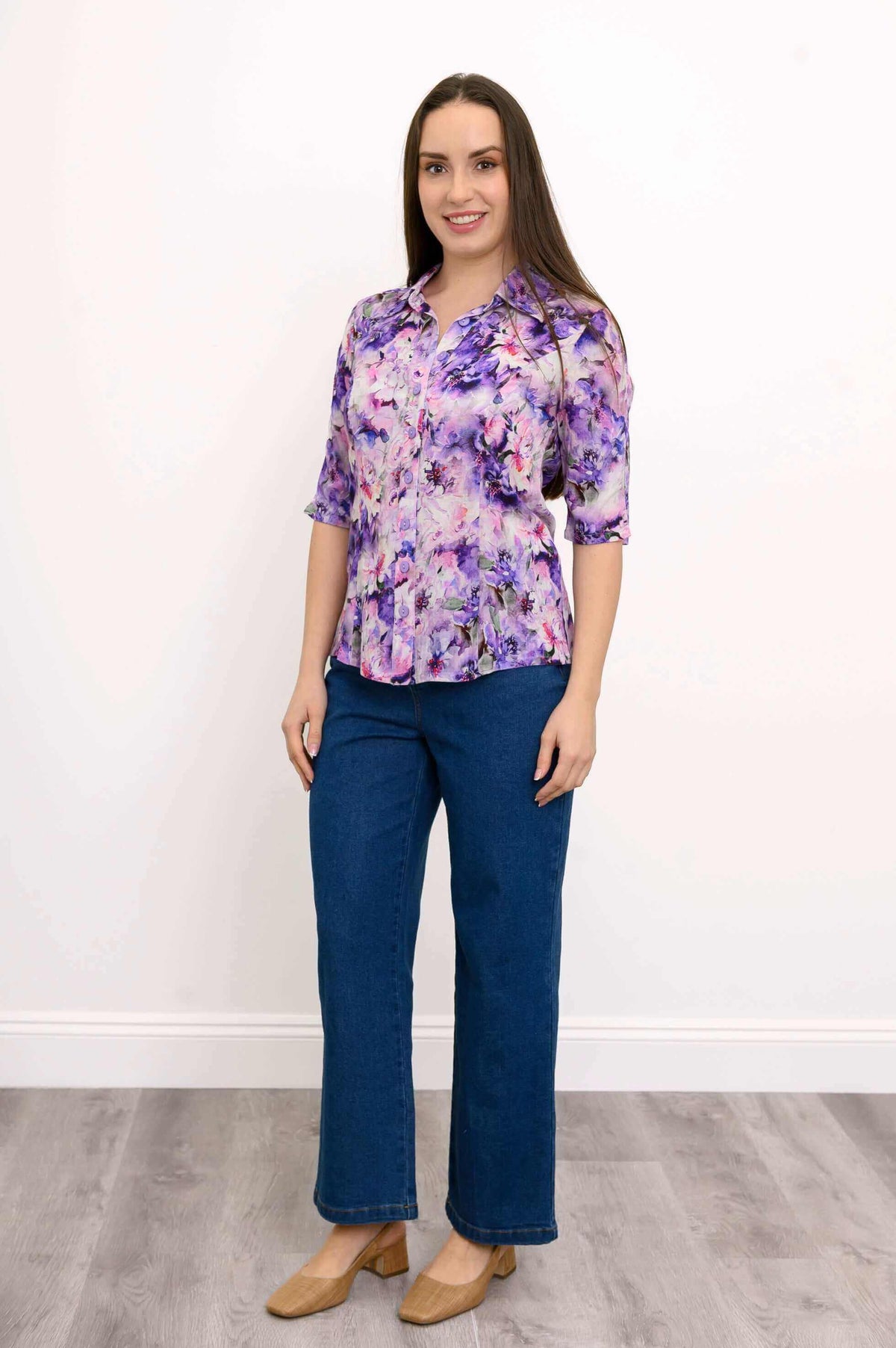 Model in purple floral blouse and blue jeans, front view with relaxed pose