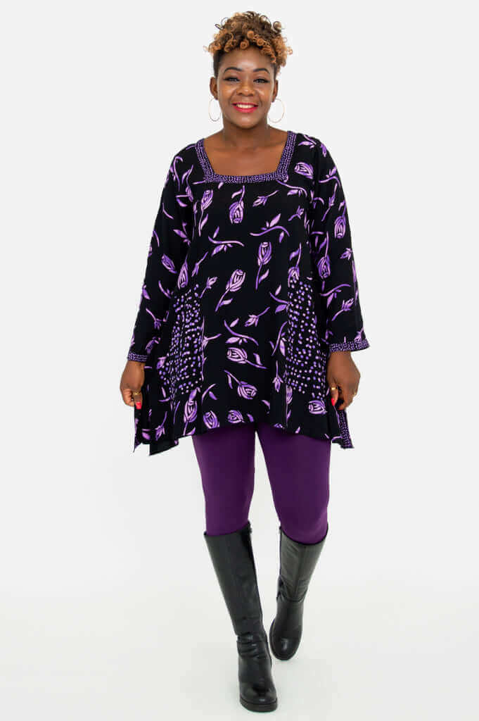 Model walking forward in Maria Tunic purple floral top and tall boots