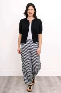 Front view of woman walking in black and white gingham pants and black cardigan