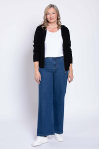Front view of wide-leg blue denim jeans styled with a white top and black hoodie