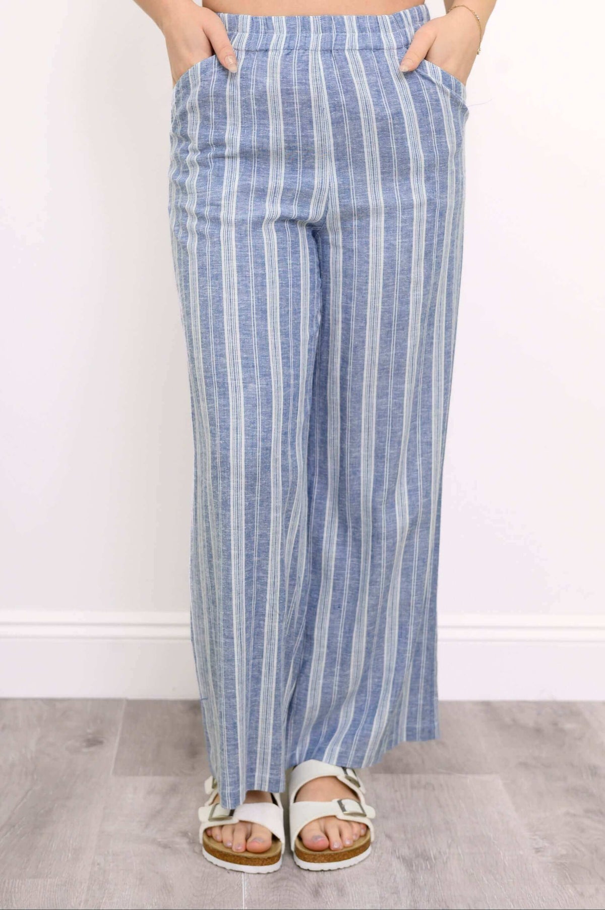 front view of woman with her hands in the pockets of her blue striped pants