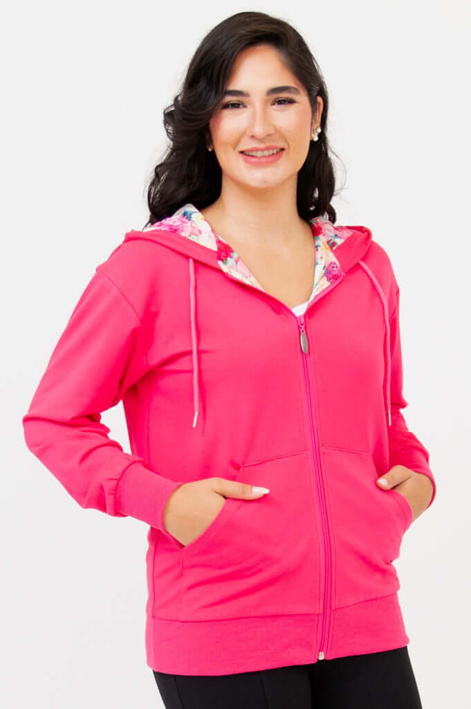 Woman wearing a fuchsia hoody with floral-lined hood, hands in pockets