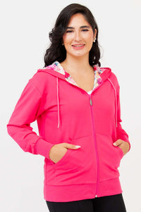 Woman wearing a fuchsia hoody with floral-lined hood, hands in pockets