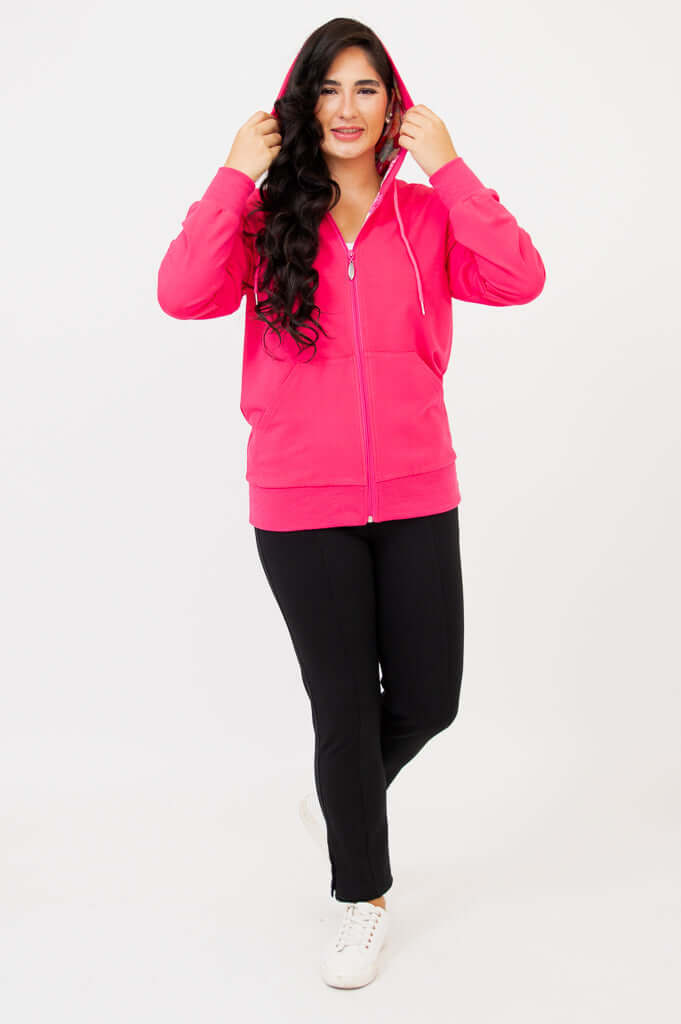 Woman standing in fuchsia hoody with hood up, hands adjusting hood