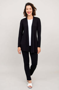 Full-body front view of woman modeling the Chopra jacket in black with pants and white sandals