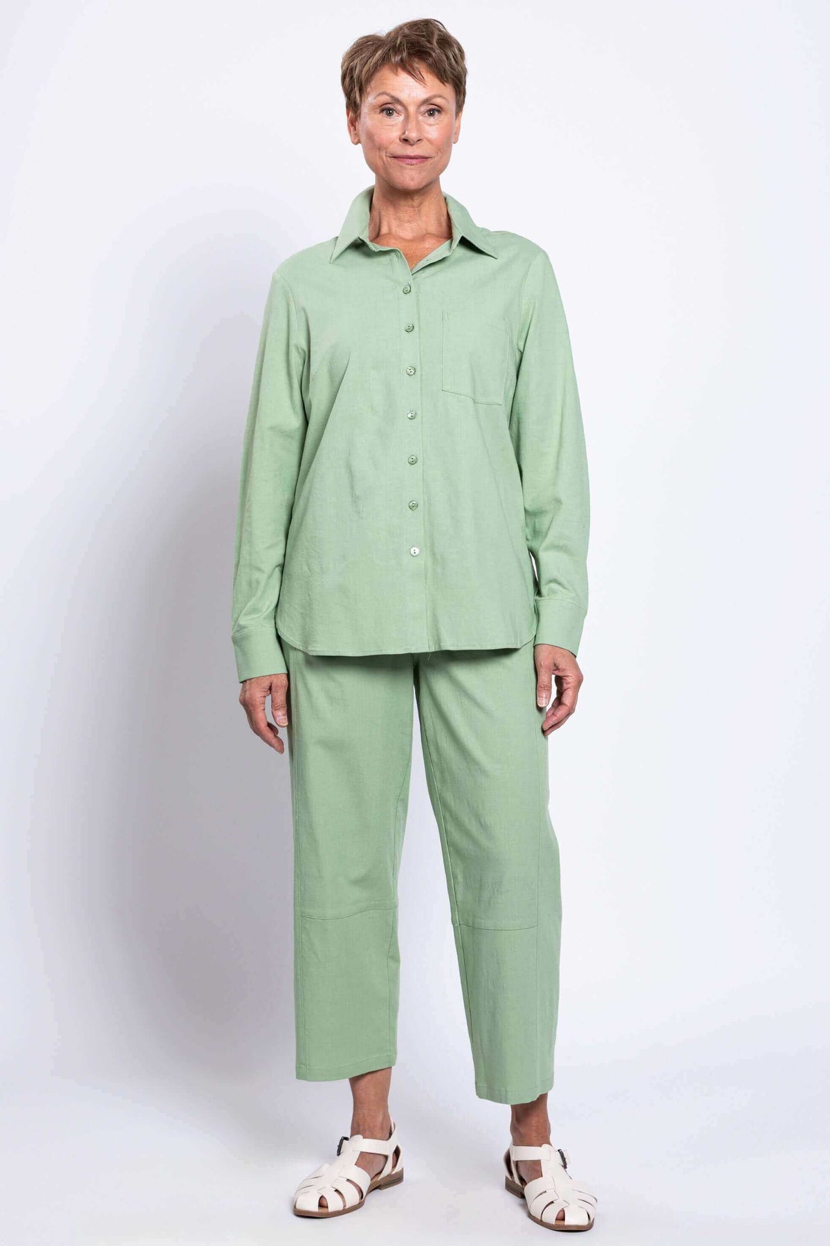 Front full-body view of woman in light green shirt and straight-leg pants