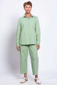 Front full-body view of woman in light green shirt and straight-leg pants