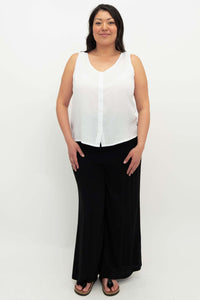 Full-body front view of woman in a white button-up tank and black wide-leg pants