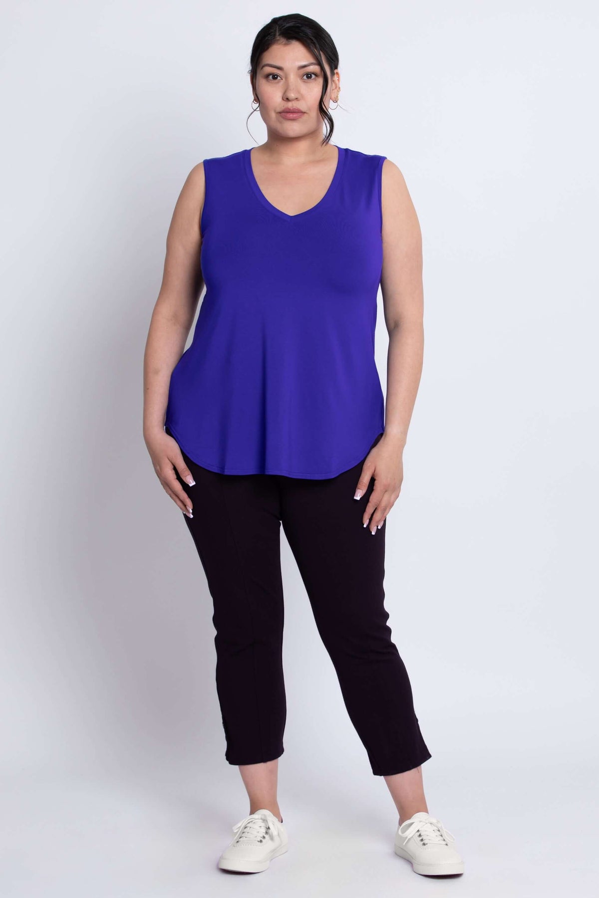 Full-body front view of woman wearing royal blue V-neck bamboo tank top and black pants.