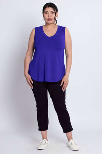 Full-body front view of woman wearing royal blue V-neck bamboo tank top and black pants.