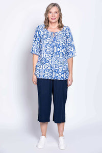 Full-body view of woman in blue and white peasant top with navy pants and white sneakers