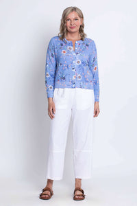 Full-length photo of woman modeling a blue floral cardigan with white pants and sandals
