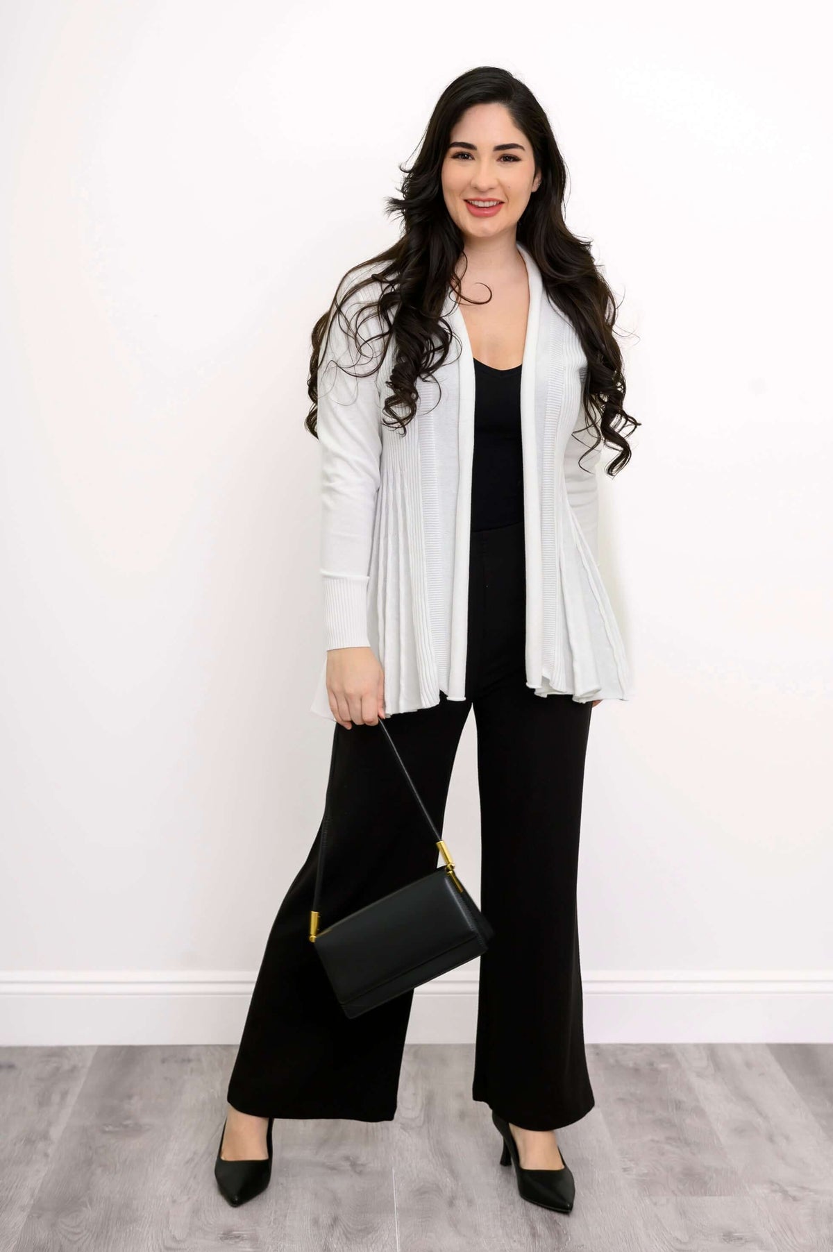 Full outfit view with white Karen Cardigan, black pants, and black handbag