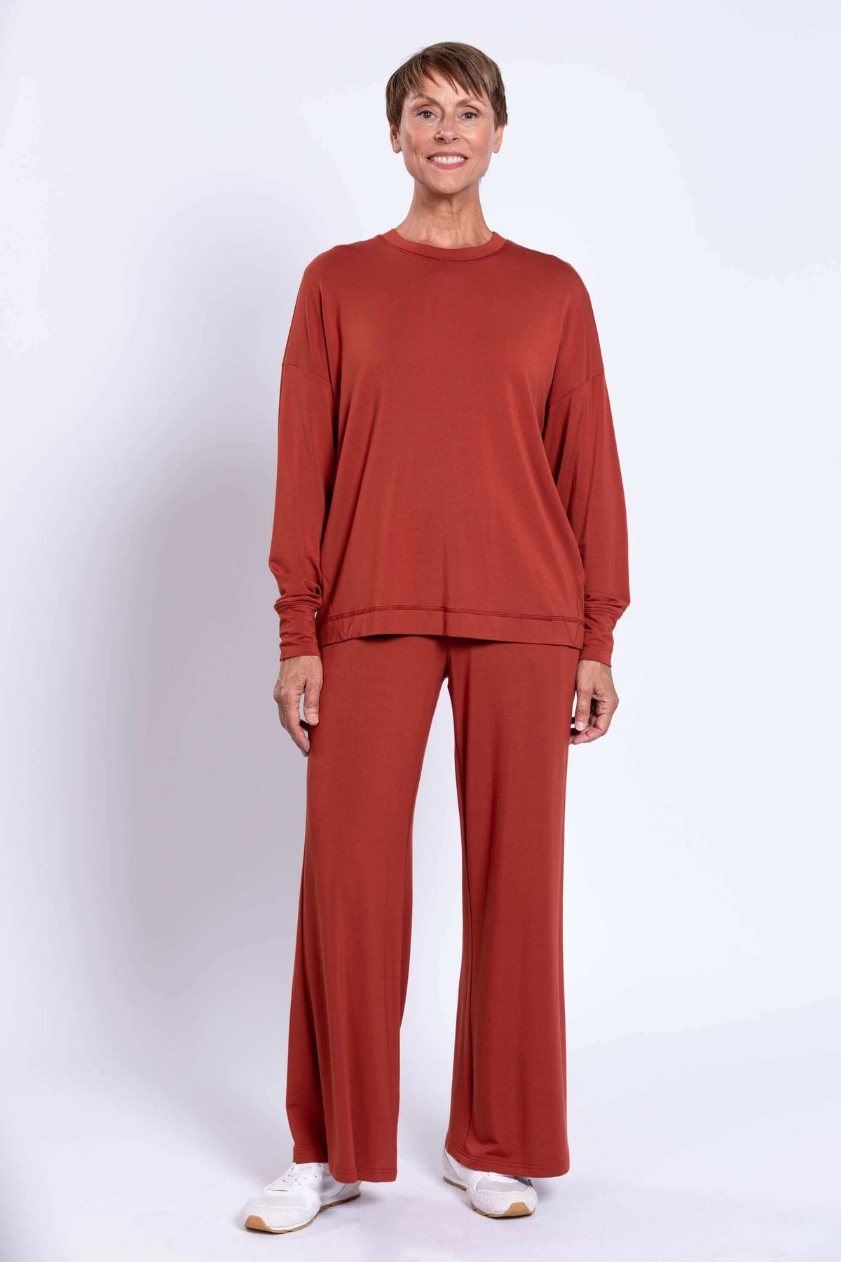 Full-body view of woman in rust bamboo crew neck top and wide-leg pants