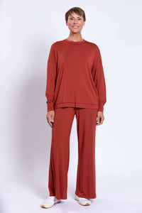 Full-body view of woman in rust bamboo crew neck top and wide-leg pants