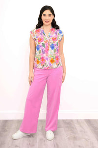 Full-body shot of a woman in a floral shawl collar top paired with pink pants
