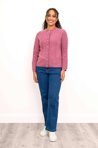 Full length view of a woman wearing a pink cashmere cable knit cardigan sweater and blue denim jeans.