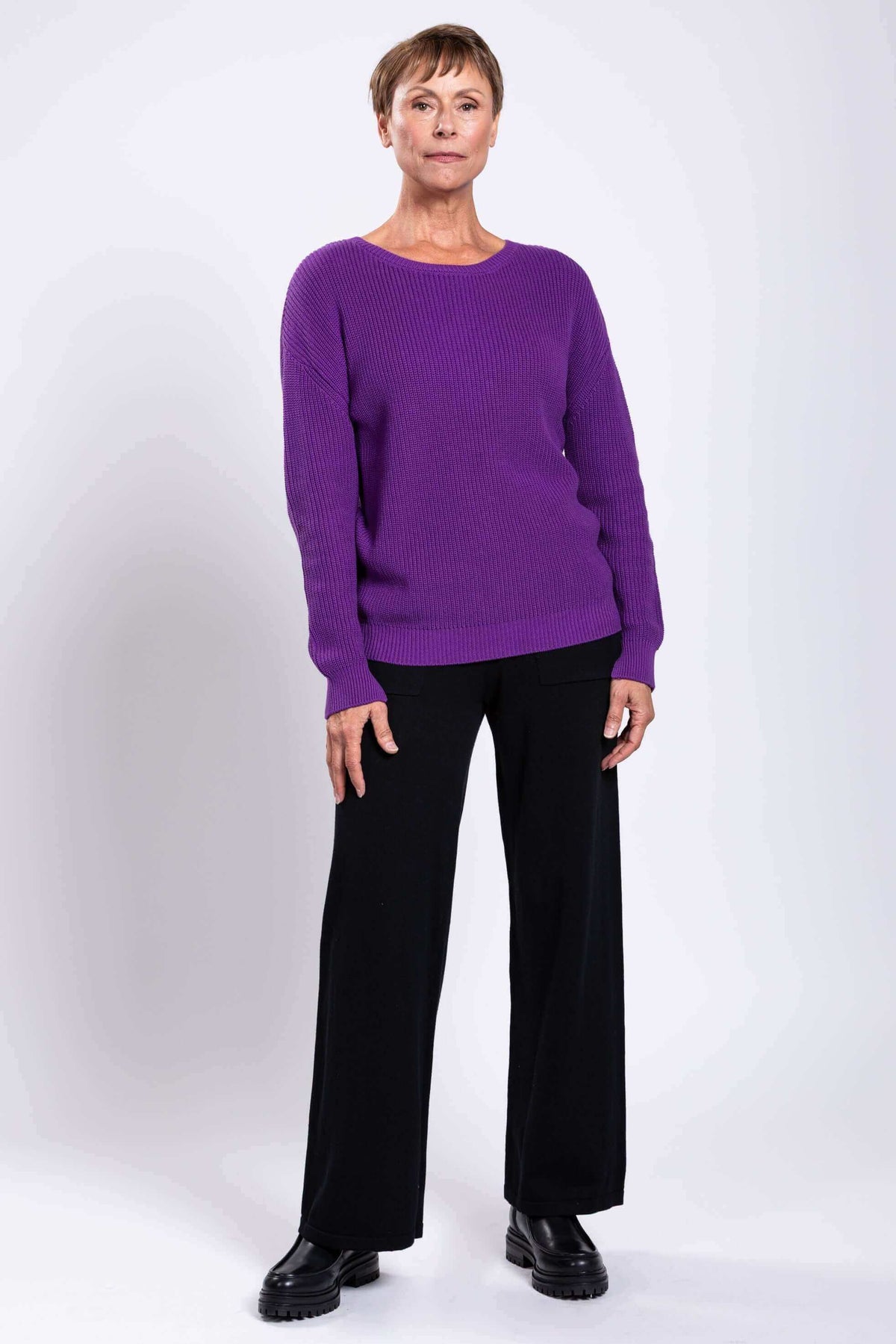 Full-body shot of woman in vibrant purple sweater and black flat shoes