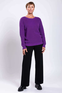 Full-body shot of woman in vibrant purple sweater and black flat shoes
