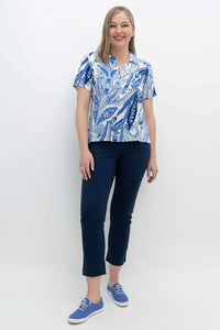 Full-body shot of a woman in a blue paisley Lala top paired with dark trousers and sneakers
