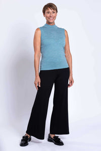 Full-body view of a woman in a sleeveless blue merino sweater and black wide-leg pants