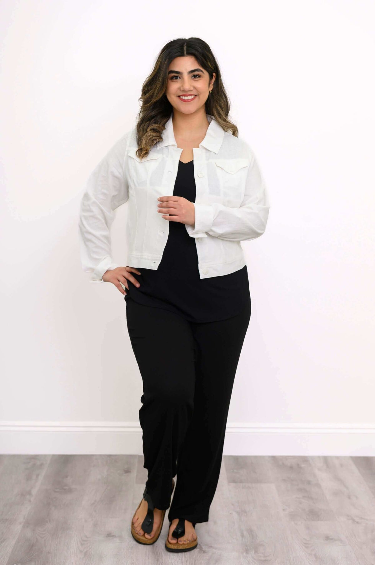 Full-body view of model in a white jean jacket and black pants, standing upright