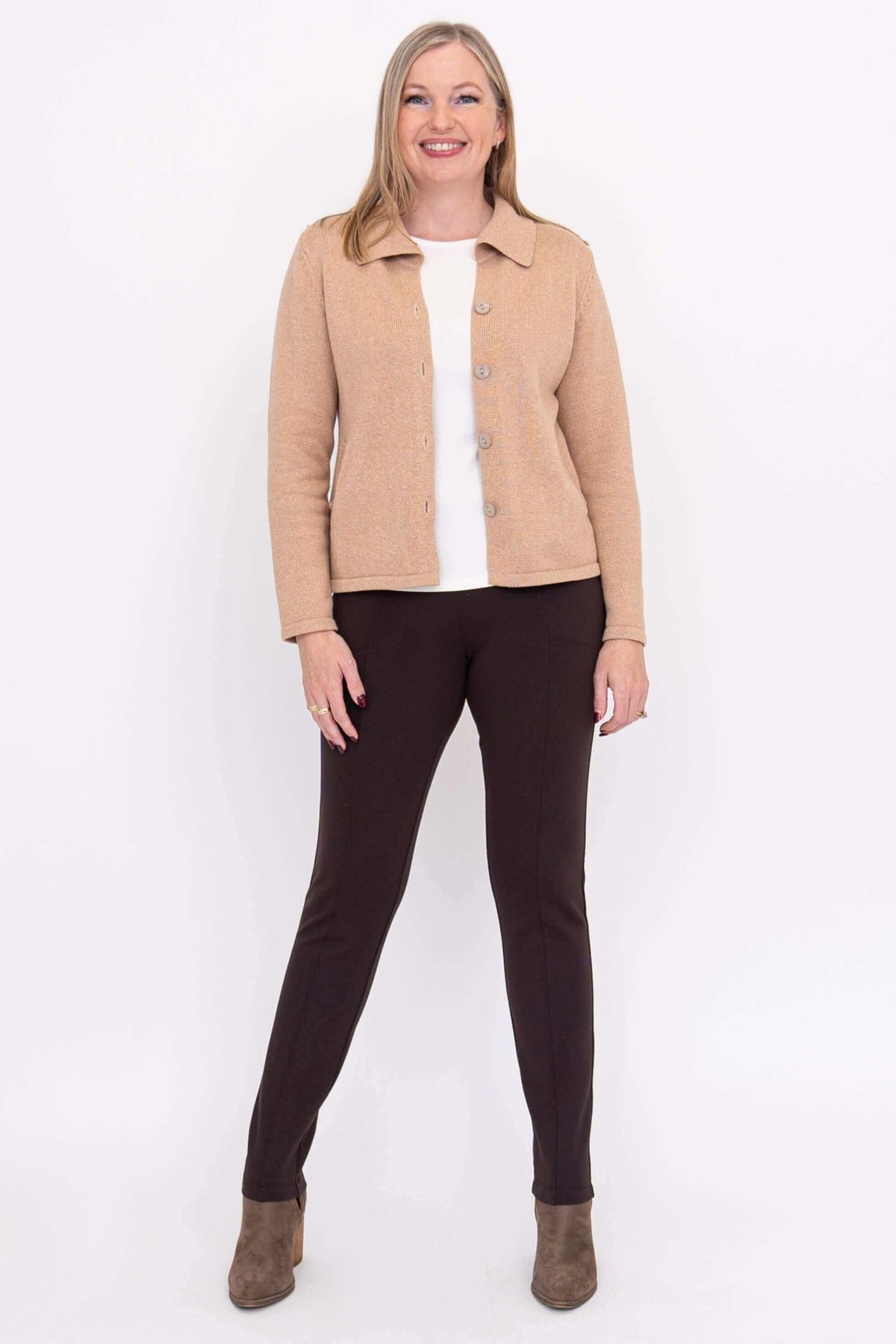 Full-body view of woman in beige cardigan, white top, and brown pants