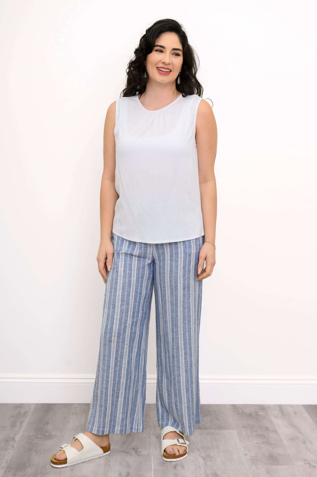 Full-body view of woman in white tank top and blue striped pants
