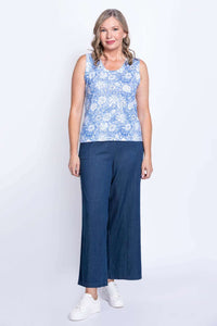 Full-body view of a woman in a blue floral tank top and wide-leg jeans