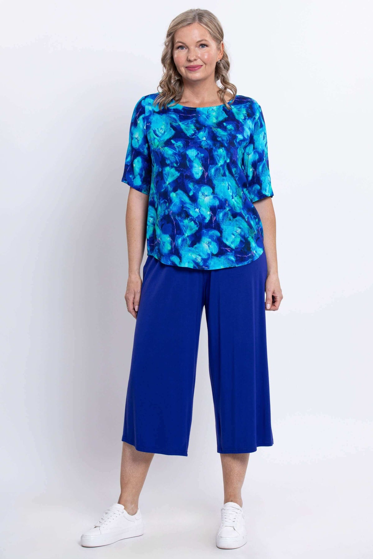 Full-length view of woman in blue watercolor blouse and loose blue pants, front view