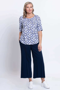 Full-length view of a woman in a blue dapple dot blouse and navy wide-leg pants