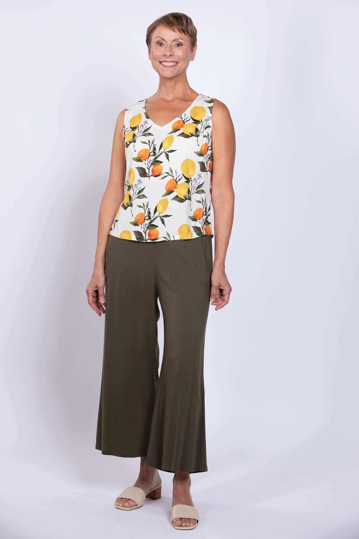 Full-length front view of woman in lemon print V-neck tank top and olive wide-leg pants