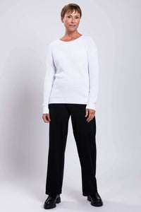 Model in a white cotton sweater and black pants, standing straight