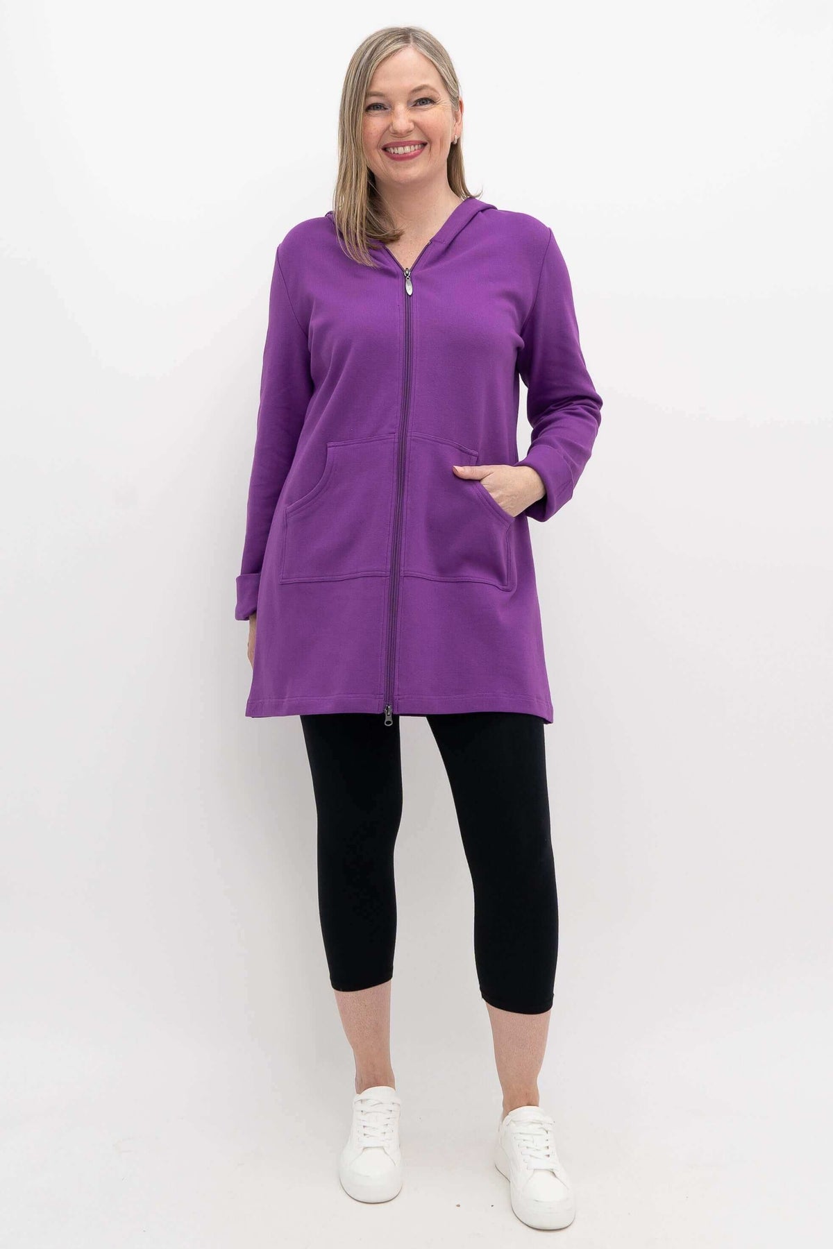 Full-length view of woman in purple hooded jacket with zipper and black leggings