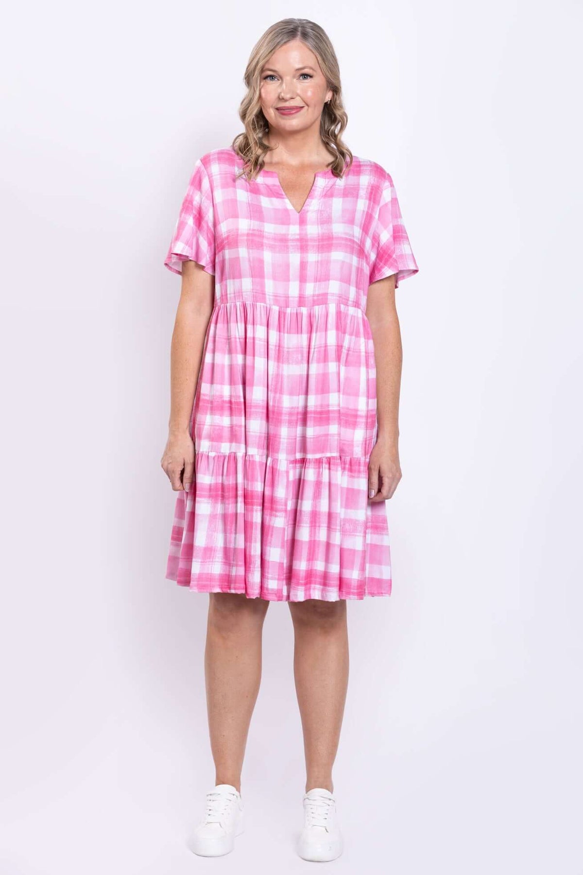 Full-length front view of woman in pink gingham checked dress, hands at side