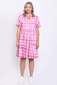 Full-length front view of woman in pink gingham checked dress, hands at side