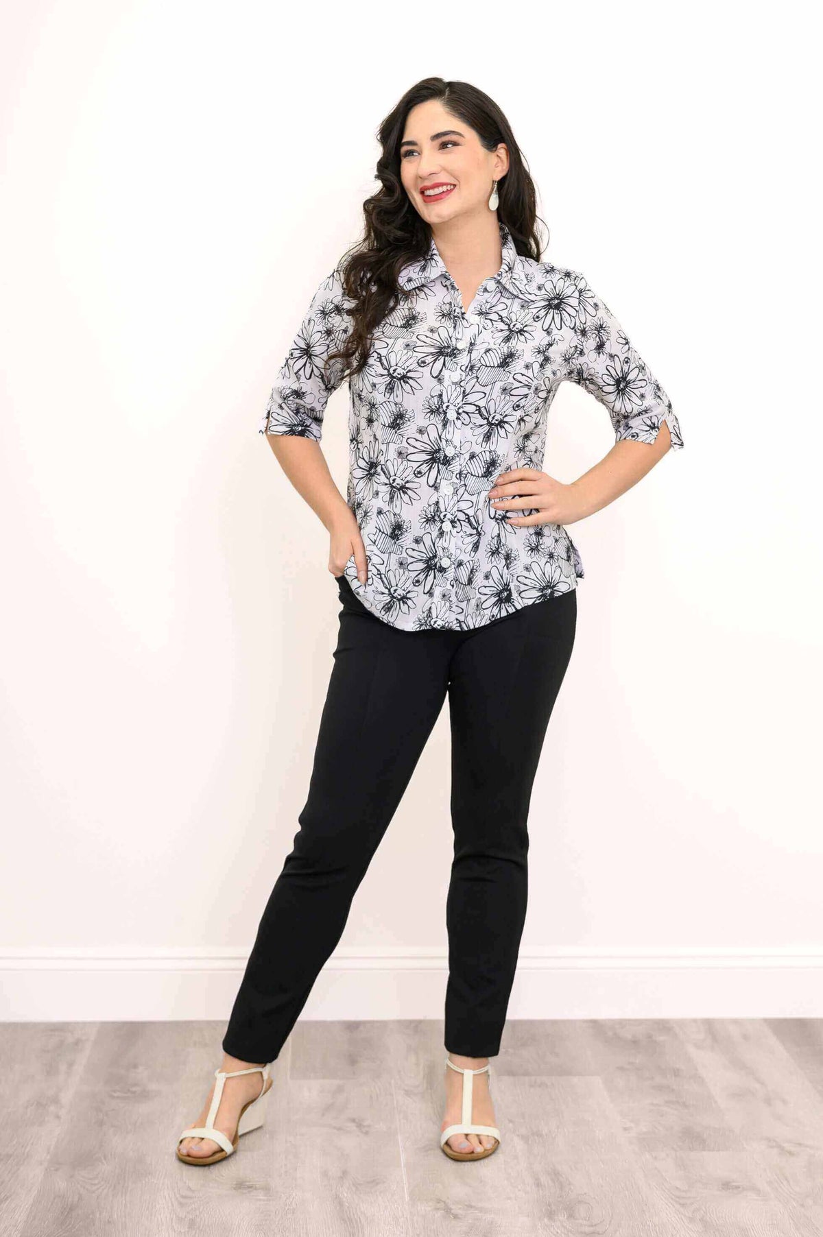 Model posing with hands on hips in a floral bamboo linen blouse and black pants