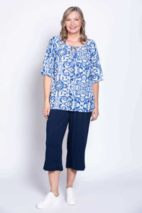 Woman in blue and white boho peasant top, standing with one foot forward, full-length