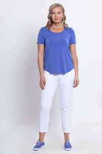 Woman standing in a full-length view wearing a blue scoop neck tee and white pants